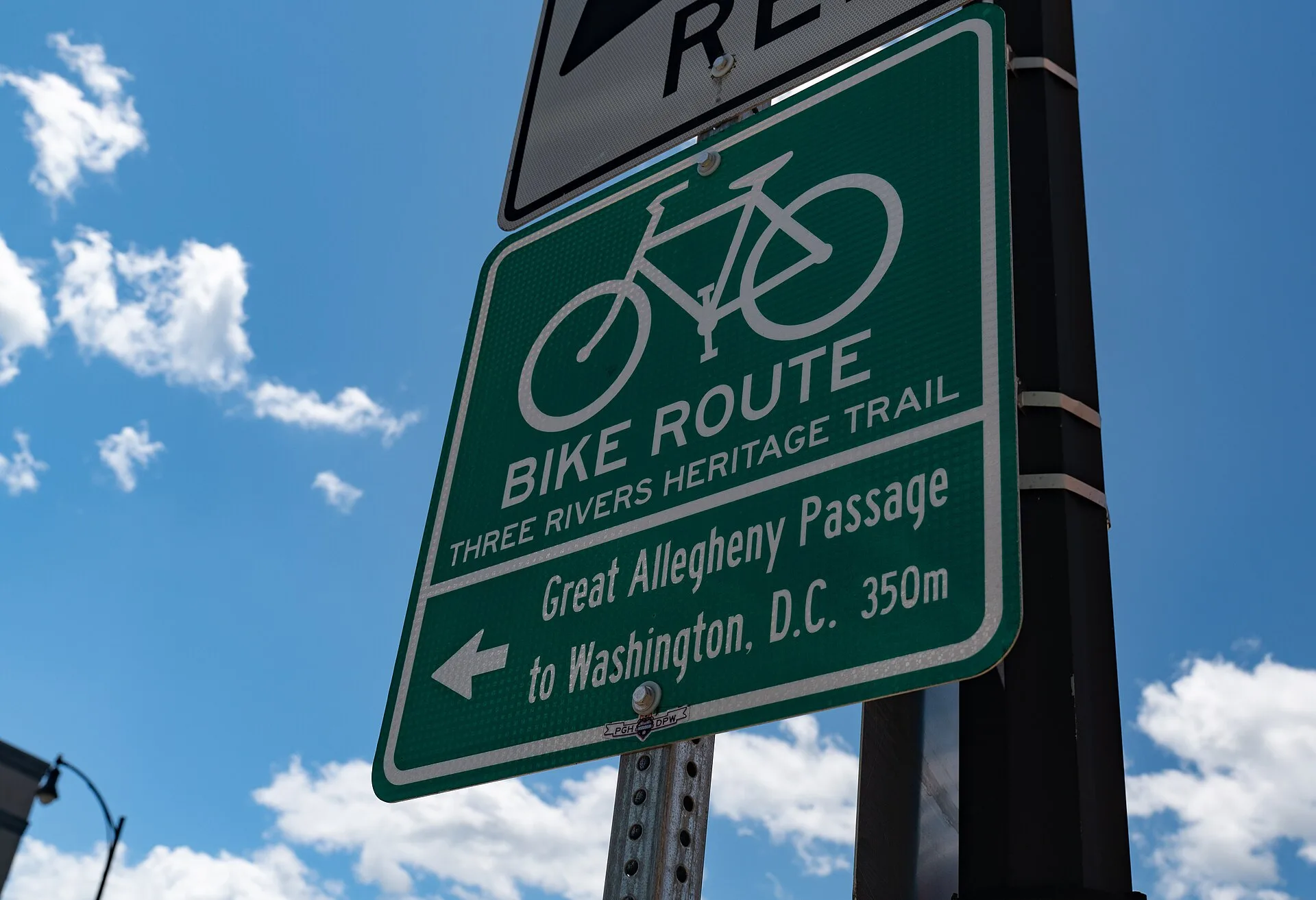 A sign for the Three Rivers Heritage Trail bicycle route and Great Allegheny Passage to Washington, D.C., at the intersection of S. Water Street and the Hot Metal Bridge, Southside, Pittsburgh, Pennsylvania. Why trail town spacing decides your daily mileage on the Great Allegheny Passage