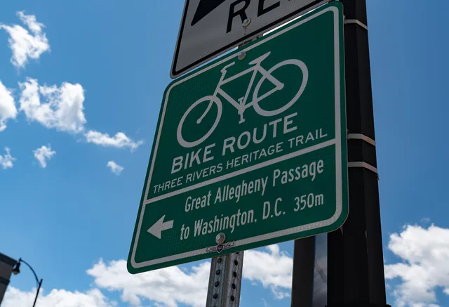 A sign for the Three Rivers Heritage Trail bicycle route and Great Allegheny Passage to Washington, D.C., at the intersection of S. Water Street and the Hot Metal Bridge, Southside, Pittsburgh, Pennsylvania. Why trail town spacing decides your daily mileage on the Great Allegheny Passage